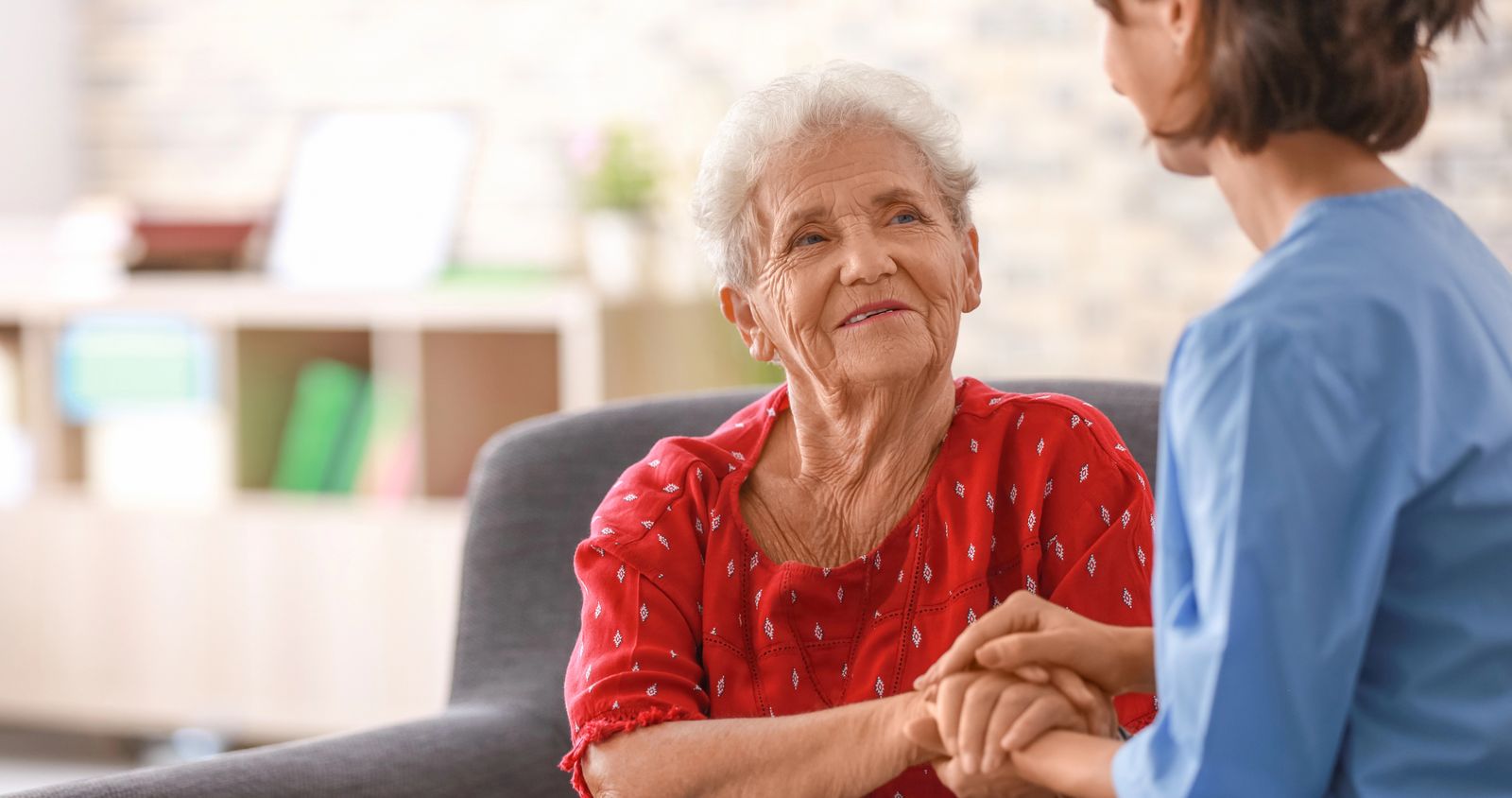 A healthcare professional gently holding the hand of an elderly patient